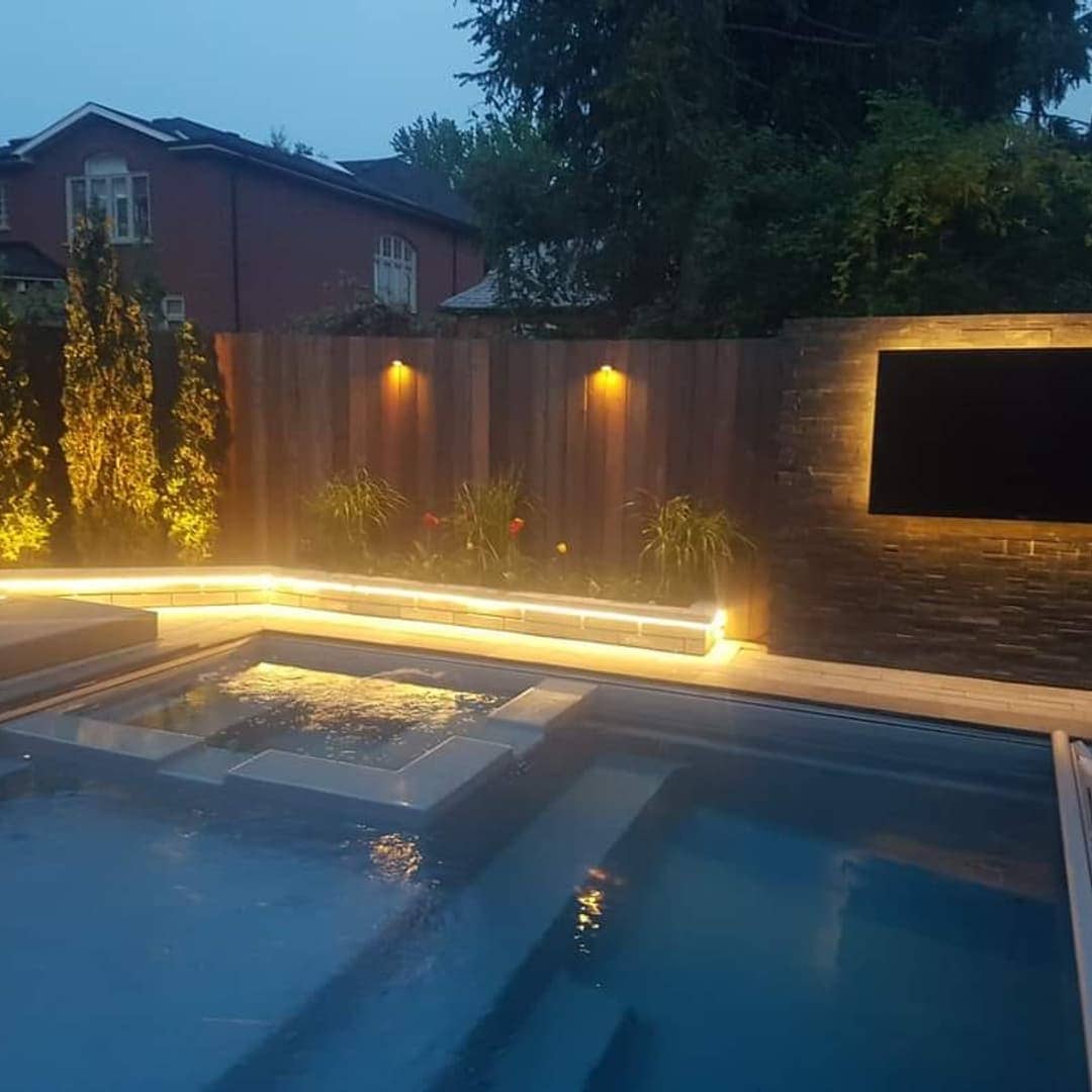 Custom backyard pool, spa, stone TV wall and integrated lighting in Ancaster, Ontario, built by Dirty Boyz