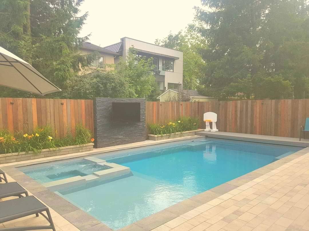 Custom backyard pool with stone TV wall and lily plantings, modern home backdrop, Ancaster ON