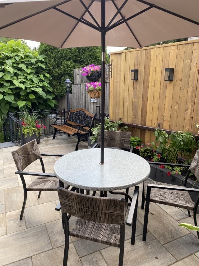 Outdoor patio with umbrella table, hanging baskets and lush garden beds