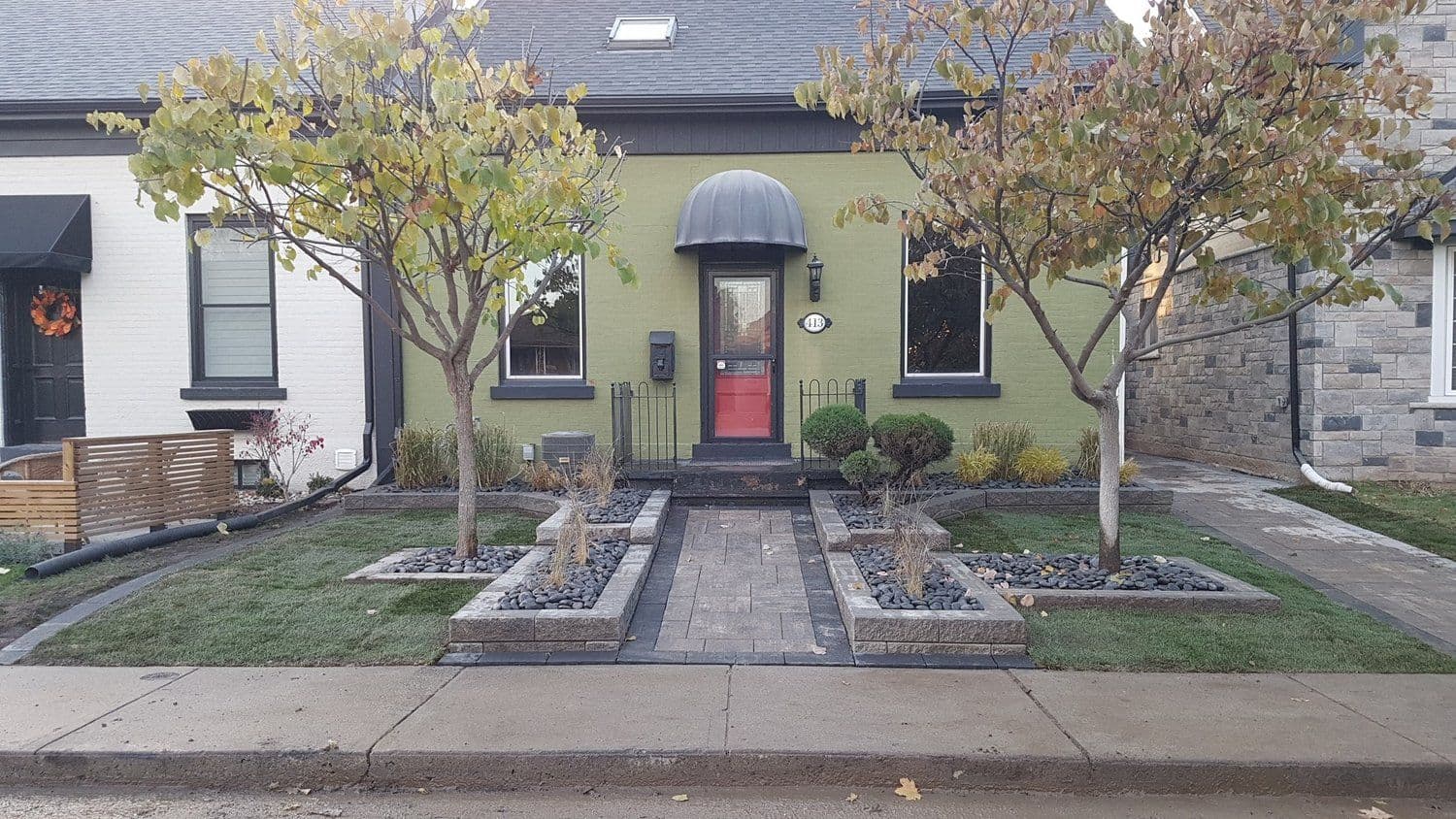 Green-painted bungalow with paver walkway, river-stone border and fresh lawn